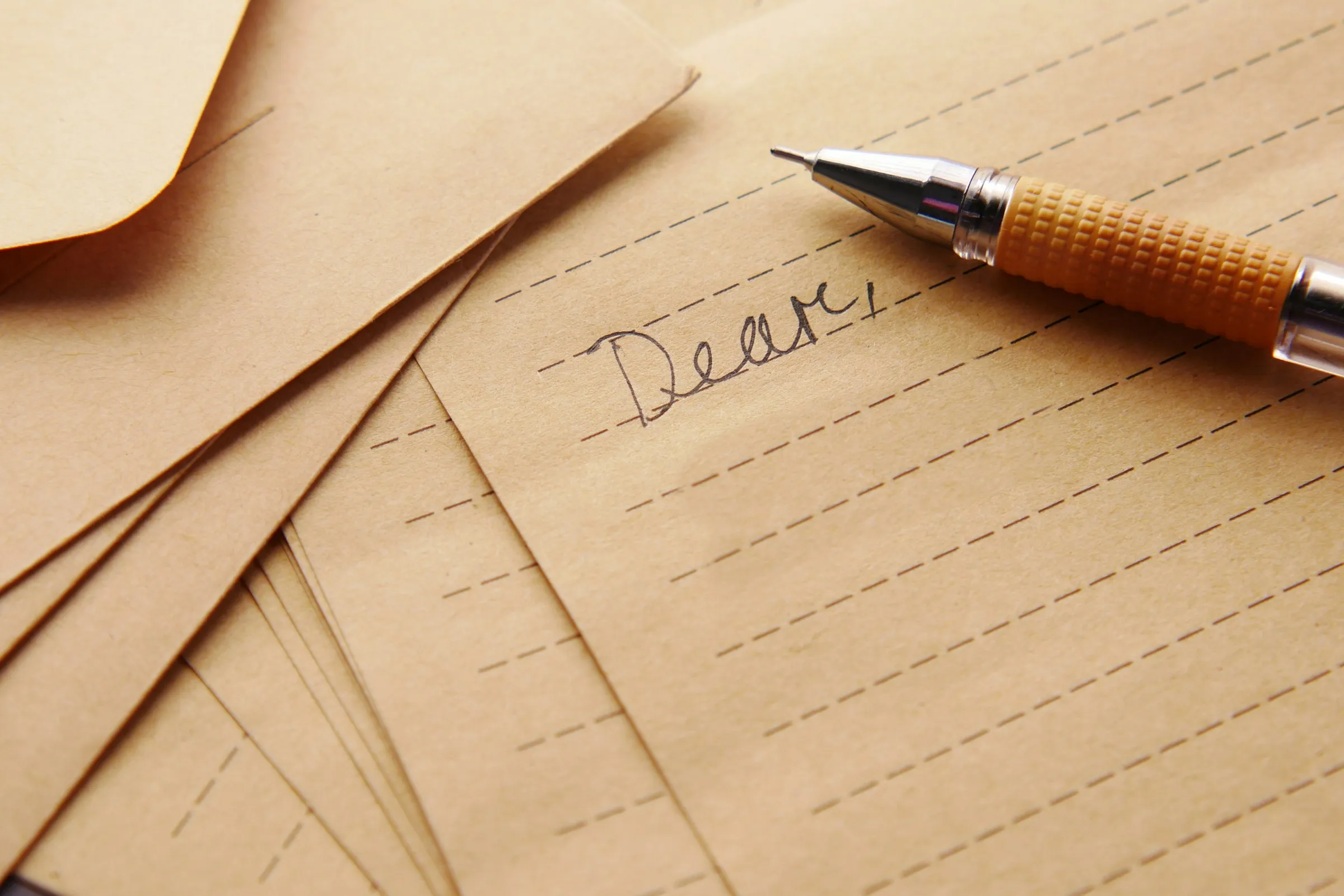 Handgeschreven brief die begint met ‘Dear’, tussen bruine enveloppen